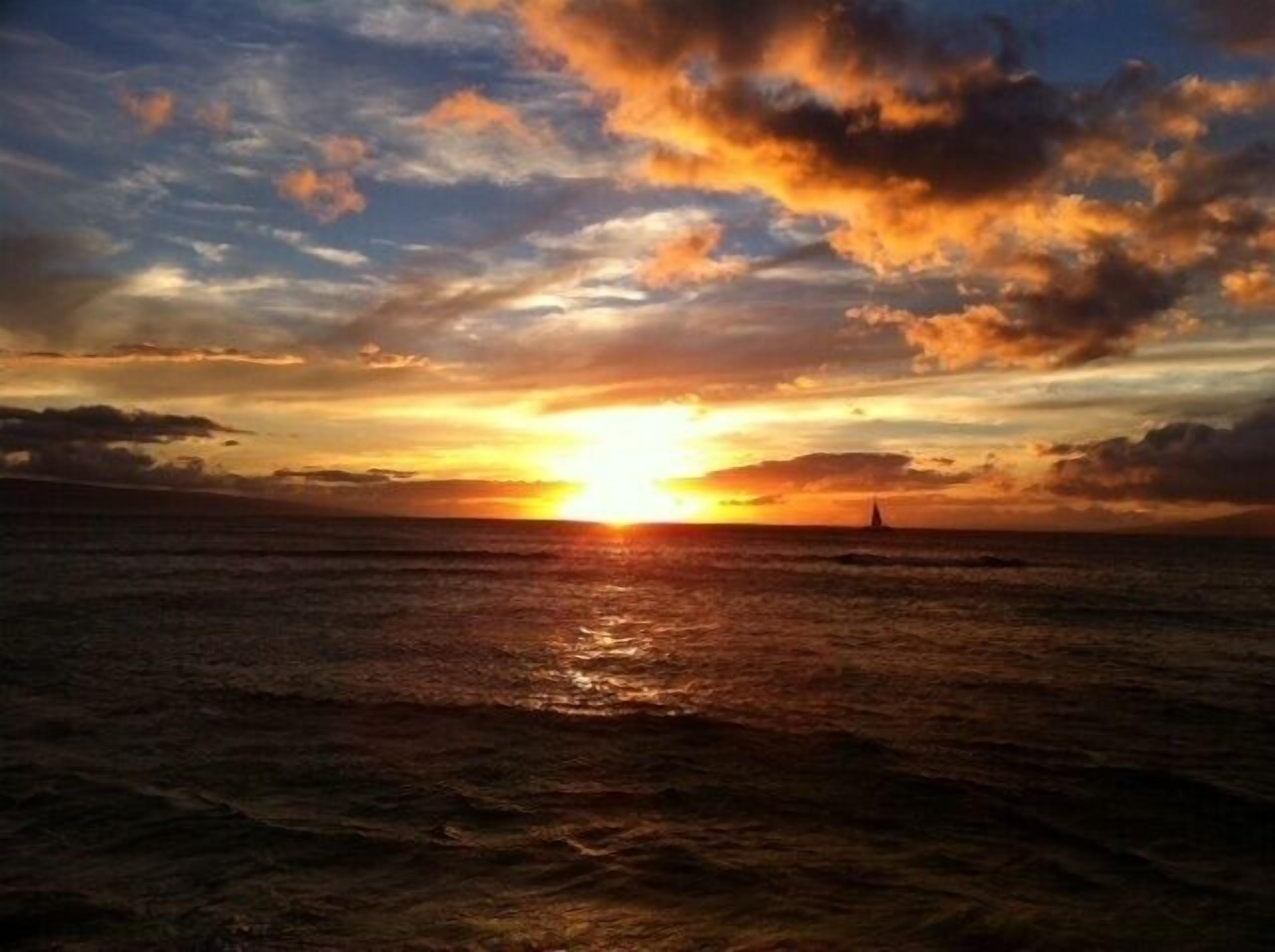 Tramonto su uno specchio d'acqua con una vela all'orizzonte.