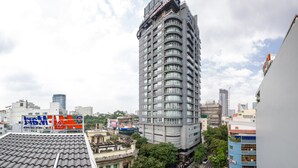 A modern high-rise building with a curved facade and multiple balconies, surrounded by other buildings and greenery.
