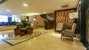 A hotel lobby with a reception desk, seating area, and a spiral staircase.