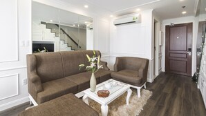 A modern living room with a brown sofa set, a white coffee table with a vase and a basket, and a large mirror reflecting a staircase.