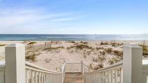 A wooden staircase leading to a beach with a clear sky. - Luxury gulf front home with huge windows facing the Gulf. Large open decks (Gulf Shores)