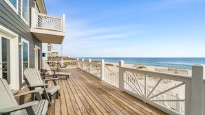 A wooden deck with Adirondack chairs, a white railing, and a view of the beach. - Luxury gulf front home with huge windows facing the Gulf. Large open decks (Gulf Shores)