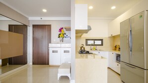 Cozinha moderna com armários brancos, geladeira de aço inoxidável e uma pequena ilha com um vaso de flores.
