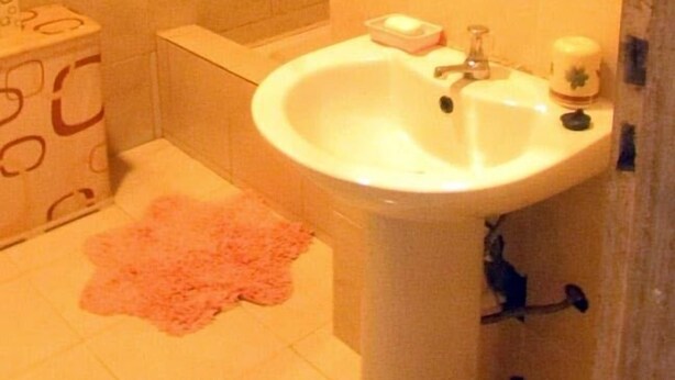 A bathroom with a white sink, a mirror, and a toilet. - Residencial Brigada (Príncipe Island)
