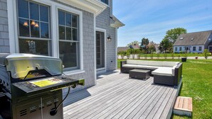 Eine Terrasse mit Grill, Sitzgelegenheiten im Freien und Blick auf eine Wohngegend.