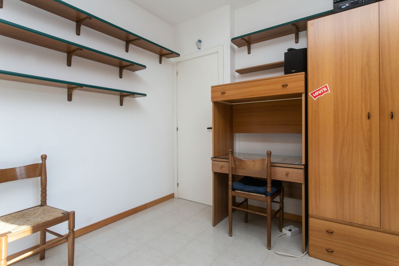 Een kamer met een stapelbed, een bureau, een stoel en een kledingkast.