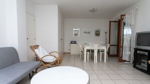 A living room with a sofa, round table, chairs, a TV, and artwork on the wall. - M148 - Marcelli, delightful villa with garden (Marcelli)