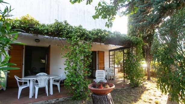 A patio with white plastic chairs, a table, and a potted plant on a tree stump. - M148 - Marcelli, delightful villa with garden (Marcelli)