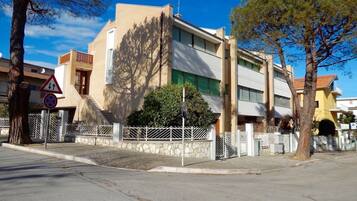 Un edificio moderno con tetto piatto, una scalinata che conduce all'ingresso e un recinto bianco che circonda la proprietà.