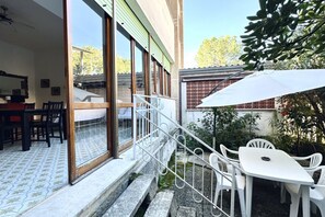 A patio area with a white table and chairs, a white umbrella, and a staircase leading to an upper level. - M145 - Marcelli, large fully equipped villa (Marcelli)