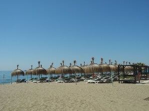 A beach with rows of sun loungers and thatched umbrellas. - La Casa de Bebita: central and with parking (FUENGIROLA)