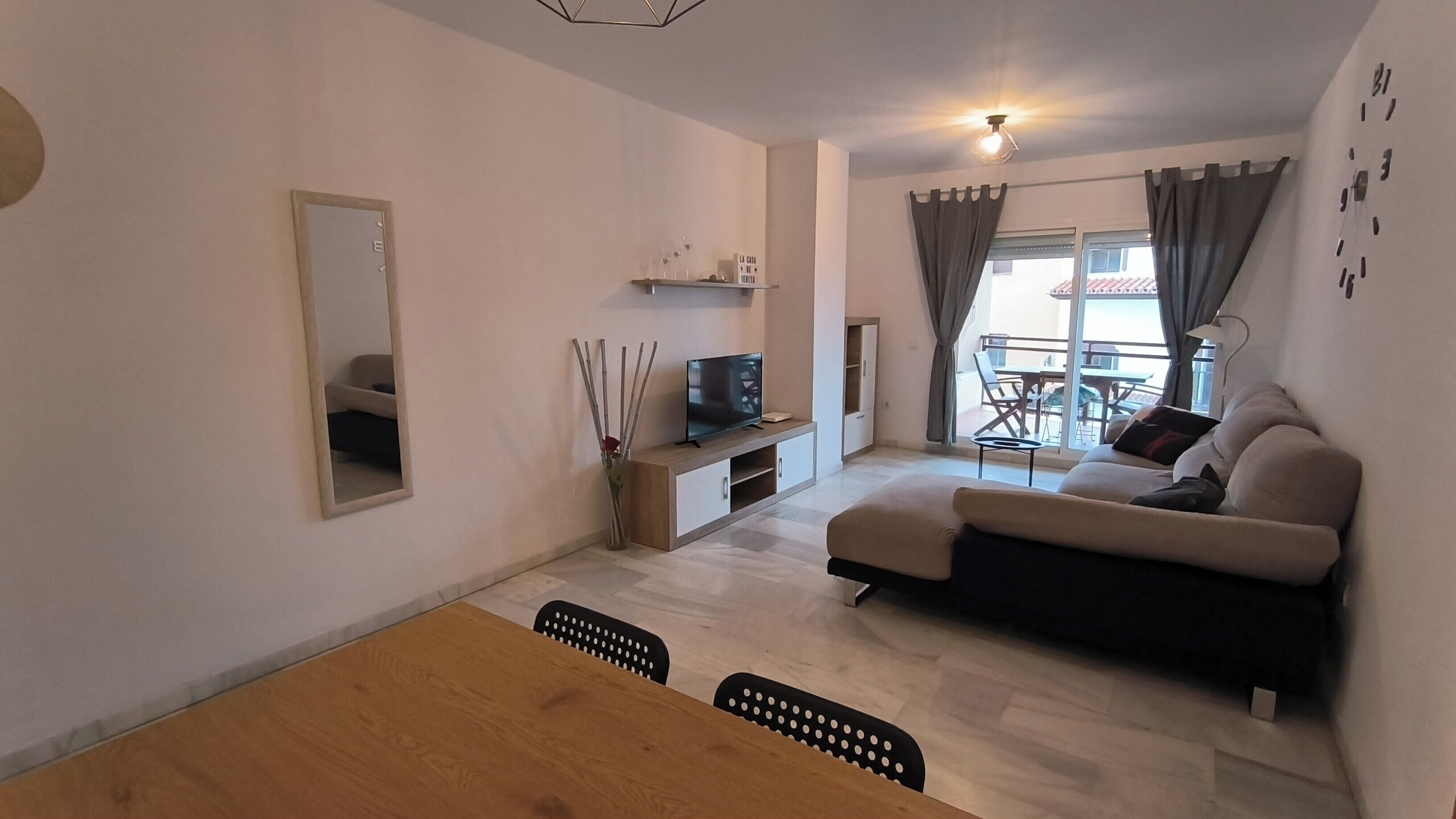 Een moderne woonkamer met een bank, televisie en eethoek.