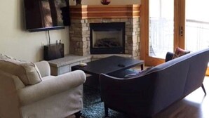 Una sala de estar con chimenea, un sofá, una mesa de centro y una televisión.