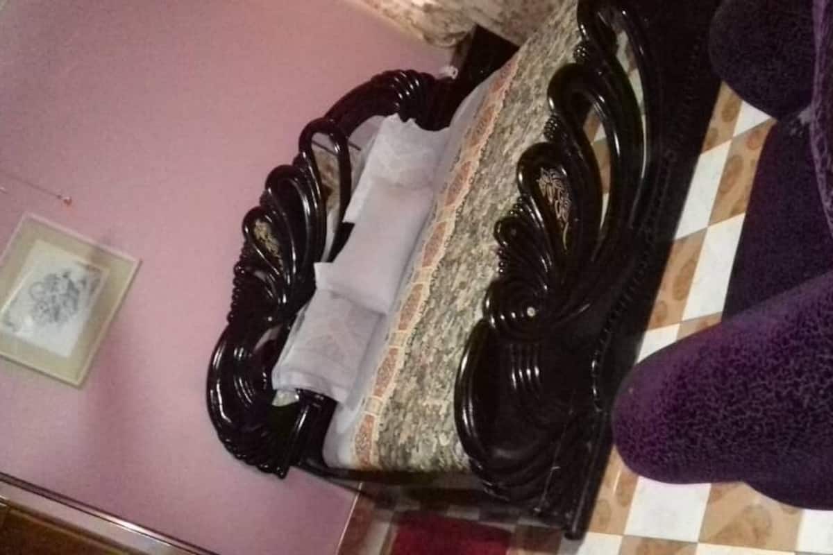 Una habitación con una cama, un sillón púrpura, un cuadro en la pared y un suelo de baldosas.