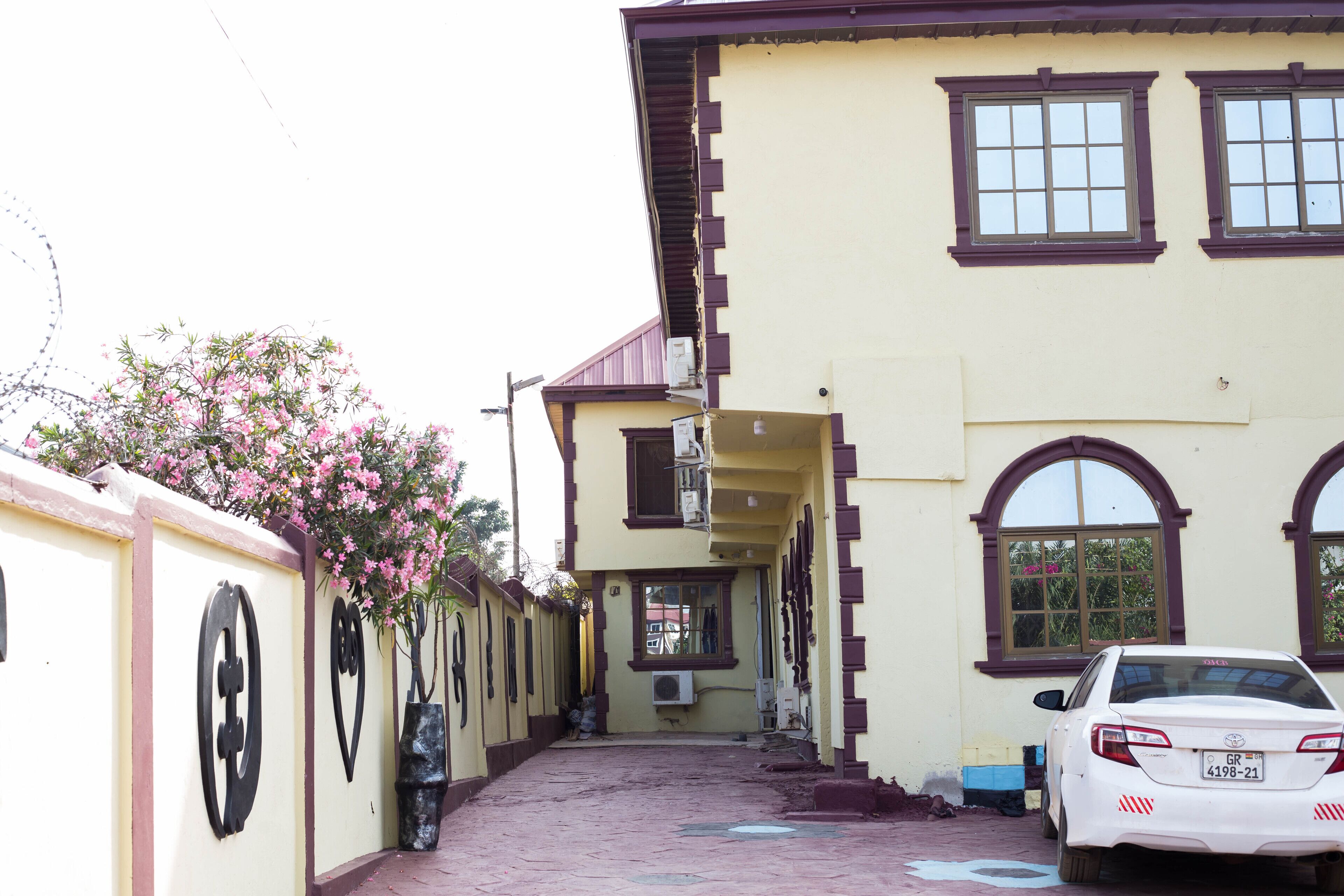 A building with a yellow facade, multiple windows, and a parked car.
