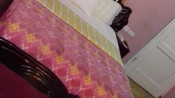 A room with a bed, a chair, a door, and a window with curtains.