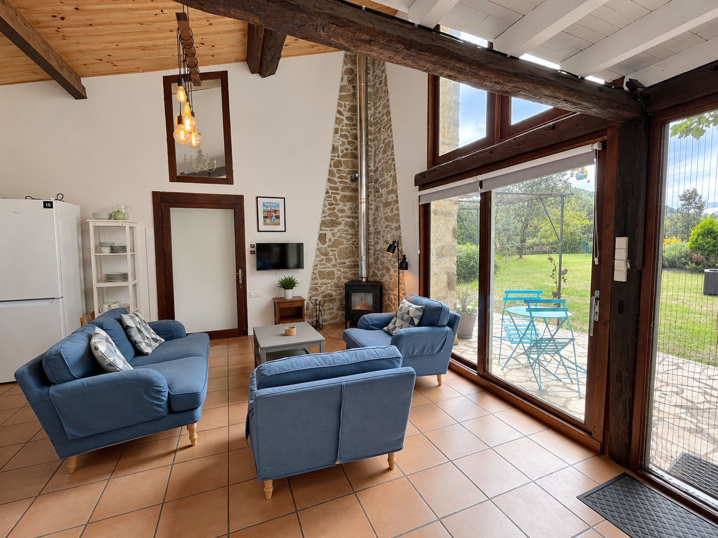 Amplia sala de estar con pared de piedra, chimenea y puerta corrediza de vidrio grande que da a un patio exterior.