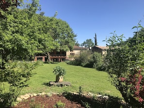 A house with a red roof, surrounded by lush greenery and a well-maintained lawn. - The gîtes are set in our little piece of paradise within its very own hamlet (Mirepoix)