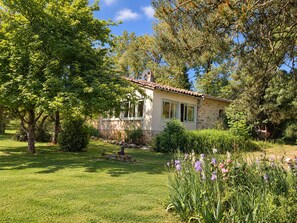 A stone house with a tiled roof, surrounded by a well-maintained garden with various plants and flowers. - The gîtes are set in our little piece of paradise within its very own hamlet (Mirepoix)