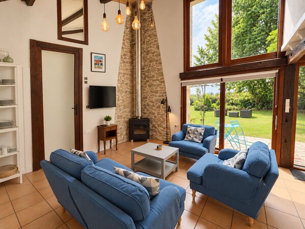 A living room with blue sofas, a fireplace, and a TV on the wall. - The gîtes are set in our little piece of paradise within its very own hamlet (Mirepoix)