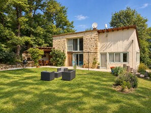 A two-story stone house with a patio, outdoor seating, and a satellite dish. - The gîtes are set in our little piece of paradise within its very own hamlet (Mirepoix)