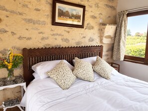 A bed with a wooden headboard, white bedding, and patterned pillows. - The gîtes are set in our little piece of paradise within its very own hamlet (Mirepoix)
