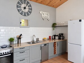 Cozinha moderna com relógio, recorte de vaca e geladeira.