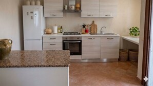 A modern kitchen with light wood cabinets, a white refrigerator, a stove, and a sink.