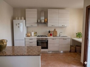 Eine moderne Küche mit hellen Holzschränken, einem weißen Kühlschrank, einem Herd und einer Spüle.