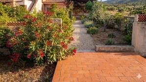 A rustic building with a stone facade, a brick pathway, and a garden with red flowers.