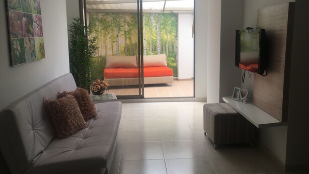 A modern living room with a sofa, a coffee table, and a TV mounted on the wall. - Gran apartamento en plaza principal (Guatape)