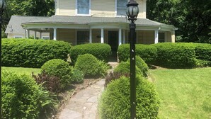 A two-story house with a covered porch and a stone pathway leading to the entrance.