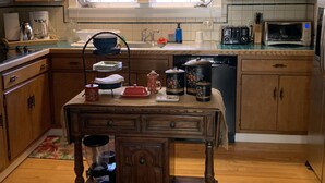 A kitchen with wooden cabinets, a window with curtains, a sink, and various kitchen appliances.