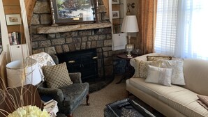 A cozy living room with a stone fireplace, a sofa, a chair, and a coffee table.