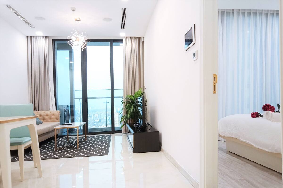 Ein modernes Hotelzimmer mit großem Fenster, einer Couch, einem Esstisch und einem Bett.