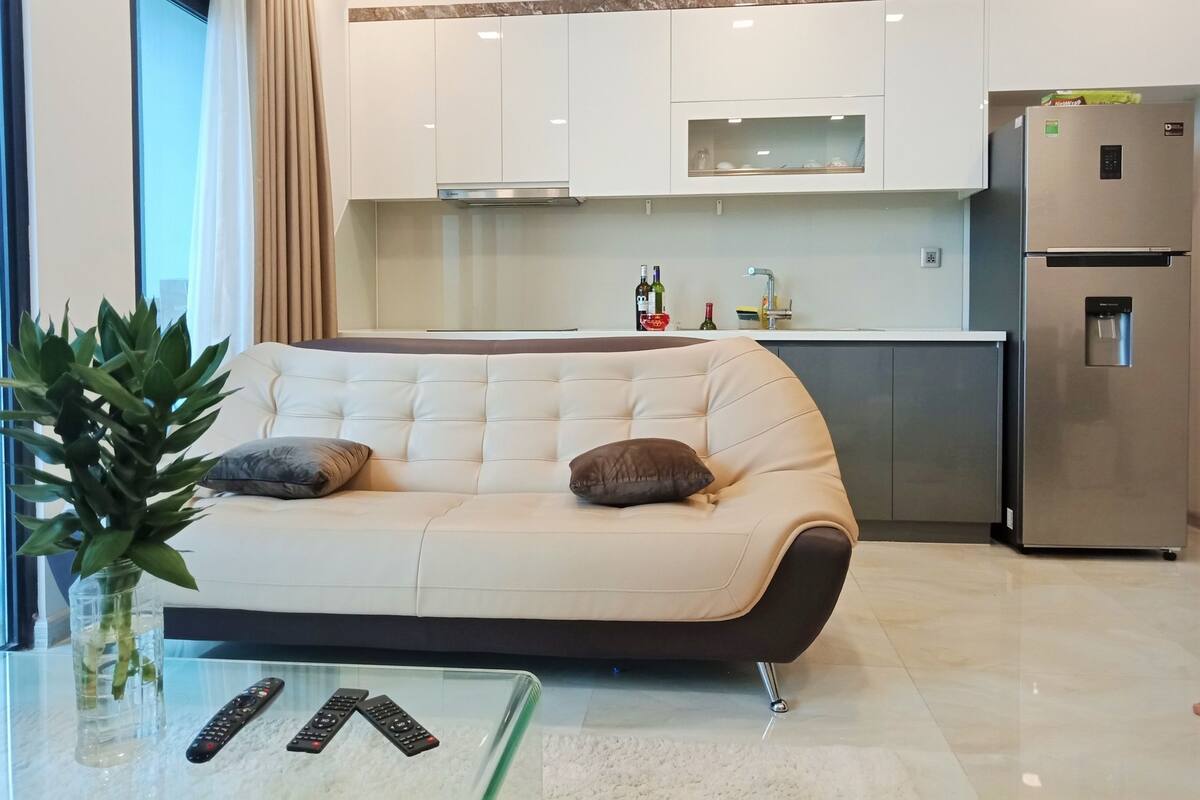Ein modernes Wohnzimmer mit einem beigen Sofa, einem Glastisch und einem Blumentopf.