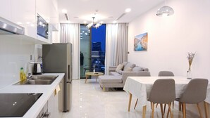 Eine moderne Küche mit Edelstahlgeräten, eine Essecke mit Tisch und Stühlen sowie ein Wohnbereich mit Sofa und einem Gemälde an der Wand.