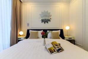 Une chambre d’hôtel avec un grand lit, deux lampes de chevet, un miroir décoratif et un magazine posé sur le lit.