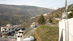 Un paisaje montañoso con una carretera, edificios y una colina nevada al fondo.