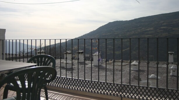 Una terraza con vistas a un paisaje montañoso, que incluye una mesa y sillas.