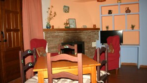 Un salón con chimenea de ladrillo, muebles de madera y un televisor sobre un mueble bajo.