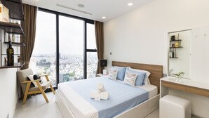 Ett modernt hotellrum med en stor säng, en sittgrupp, ett sminkbord och utsikt över staden.
