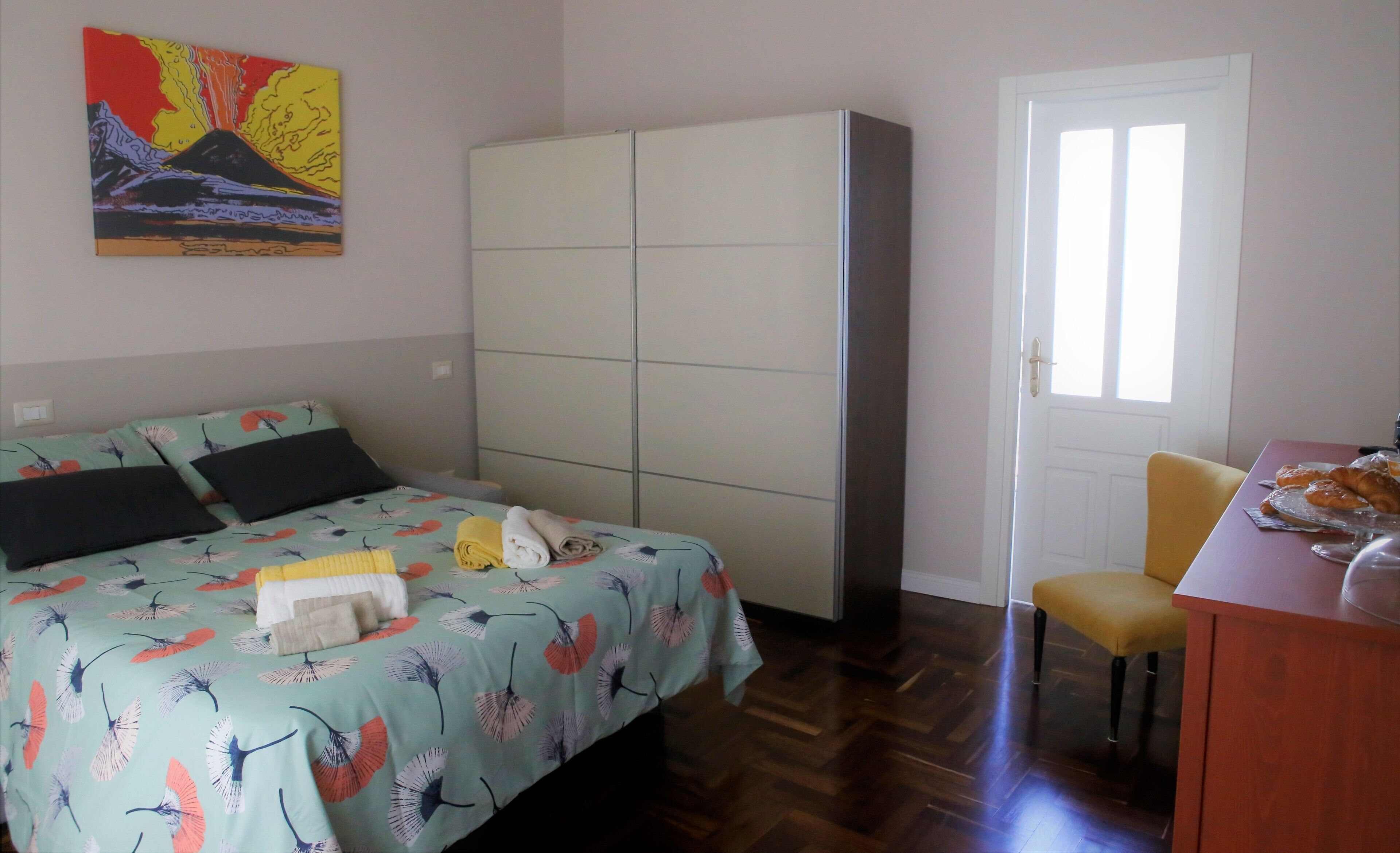 Un dormitorio con una cama, un armario, un escritorio con silla y una ventana.