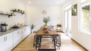 Una cocina moderna con una mesa de madera, armarios blancos y una planta en maceta.