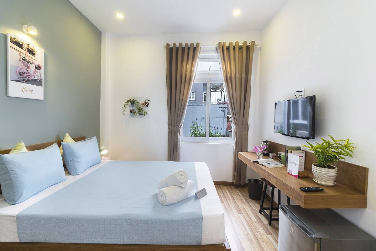 A hotel room with a bed, a desk, a TV, and a window with curtains.