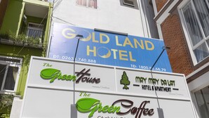 Un letrero de hotel con la marca 'Gold Land Hotel' y 'The Green Coffee'.