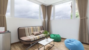 Una sala moderna con un sofá, una mesa de centro, un sillón de peluche verde y una planta en maceta.