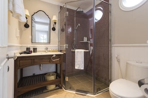 Une salle de bain avec une douche à parois de verre, des toilettes blanches et un meuble-lavabo en bois avec un miroir.