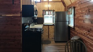 Una cucina compatta con pareti in legno, un fornello, un lavello e un frigorifero.