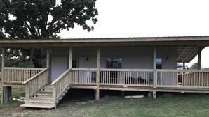 Una struttura in legno a due piani con un portico coperto e una scala che conduce al piano superiore.